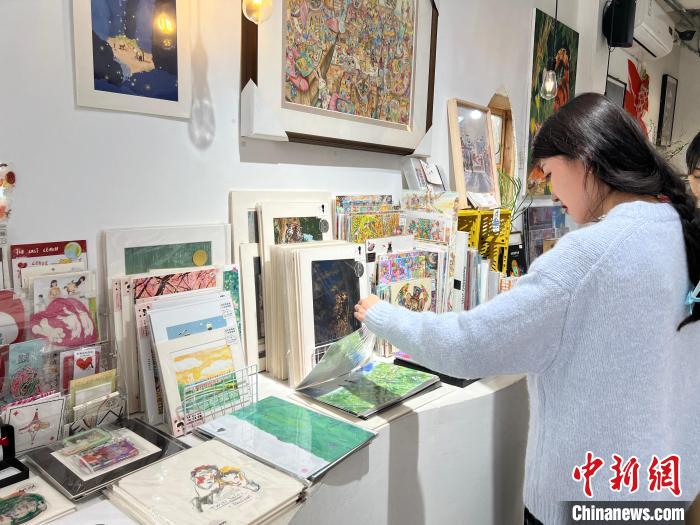 圖為藝術(shù)品商店內(nèi)，顧客挑選插畫作品?！＄婌?攝