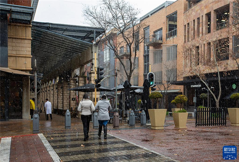 7月10日，在南非約翰內(nèi)斯堡一處商業(yè)區(qū)，人們在雪中行走。新華社記者 張譽東 攝