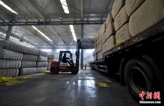 新疆喀什綜合保稅區(qū)，喀什啟路國際貿(mào)易有限公司的倉庫內(nèi)，工人正在裝載從塔吉克斯坦和烏茲別克斯坦進口的棉花。劉新攝