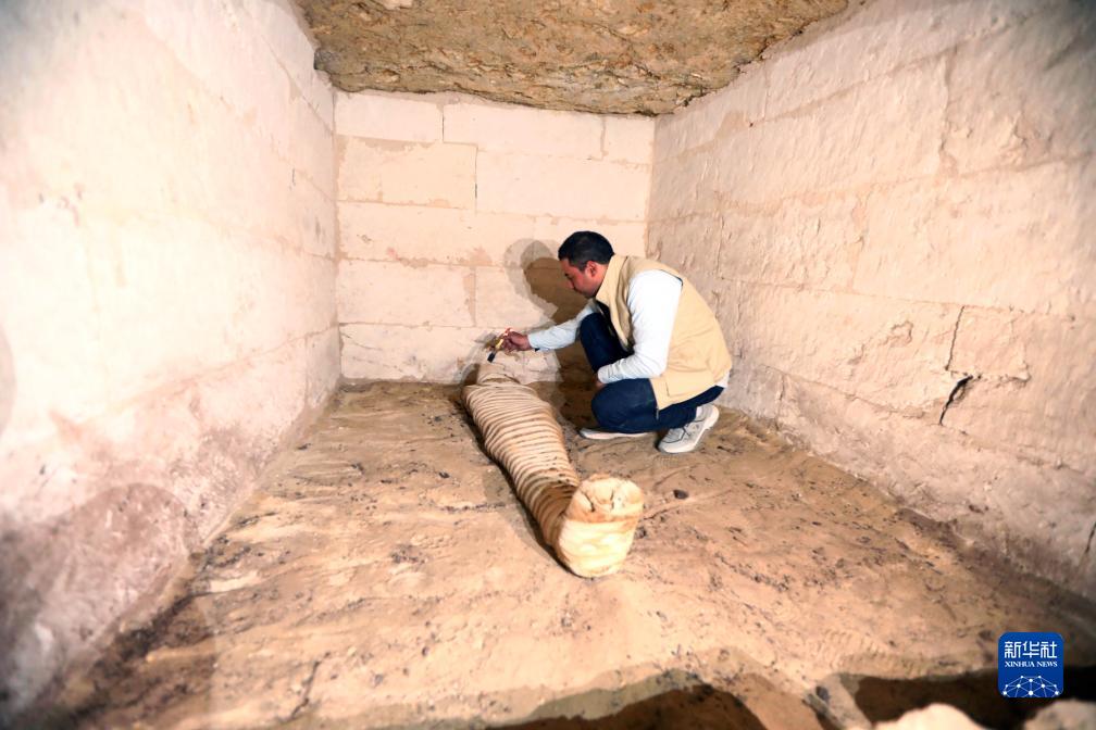 10月15日，在埃及明亞省考古現(xiàn)場(chǎng)，考古人員清理一座石鑿墓中的木乃伊。新華社發(fā)（艾哈邁德·戈馬攝）