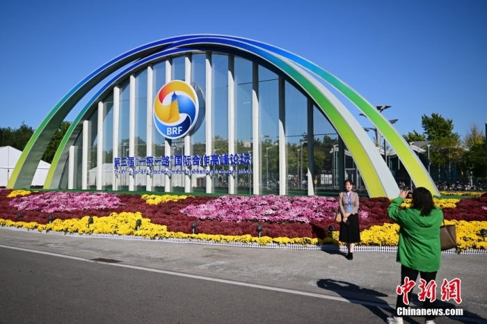 10月15日，北京，工作人員在國家會議中心外的第三屆“一帶一路”國際合作高峰論壇景觀布置前拍照留念。當日，位于國家會議中心的第三屆“一帶一路”國際合作高峰論壇新聞中心啟動試運行。據(jù)悉，第三屆“一帶一路”國際合作高峰論壇將于10月17日至18日在北京舉行。<a target='_blank' href='/'><p  align=