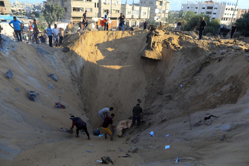 10月16日，在加沙地帶南部城市汗尤尼斯，人們?cè)谠庖陨幸u擊后的建筑廢墟中救援傷者。 新華社發(fā)（亞西爾·庫(kù)迪 攝）