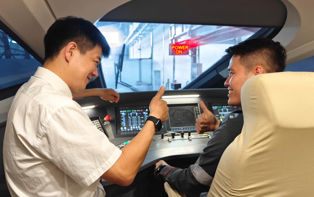 8月25日，在印度尼西亞萬隆的雅萬高鐵德卡魯爾動車所內(nèi)，中國師傅穆振（左）在向印尼火車司機塞蒂亞萬講解動車組出庫前的上電作業(yè)。