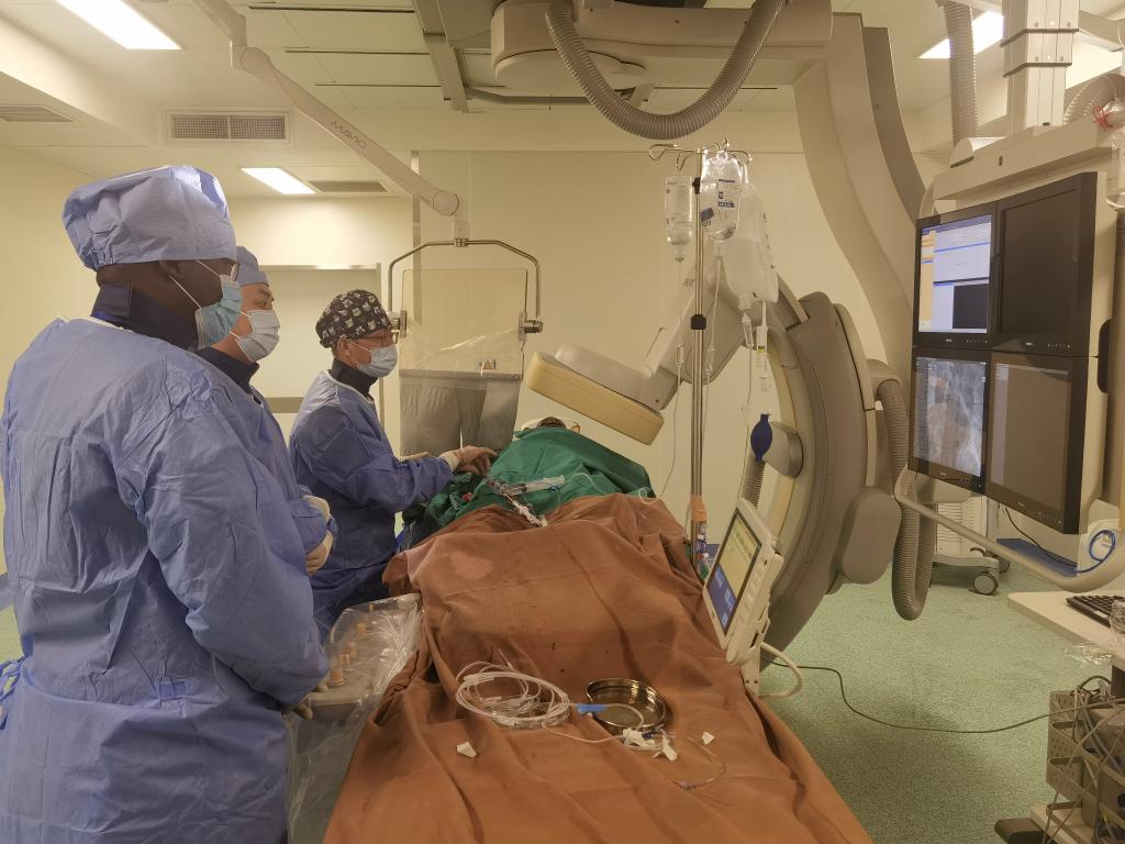 中國第29批援幾內亞醫(yī)療隊隊員、首都醫(yī)科大學附屬北京天壇醫(yī)院心內科副主任醫(yī)師王汝朋（右一）正在給患者做手術。（北京天壇醫(yī)院供圖）