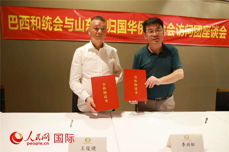 中國僑聯(lián)副主席、山東省僑聯(lián)主席李興鈺（右）與巴西和統(tǒng)會會長王俊曉簽署合作協(xié)議書。人民網(wǎng)記者 陳海琪攝