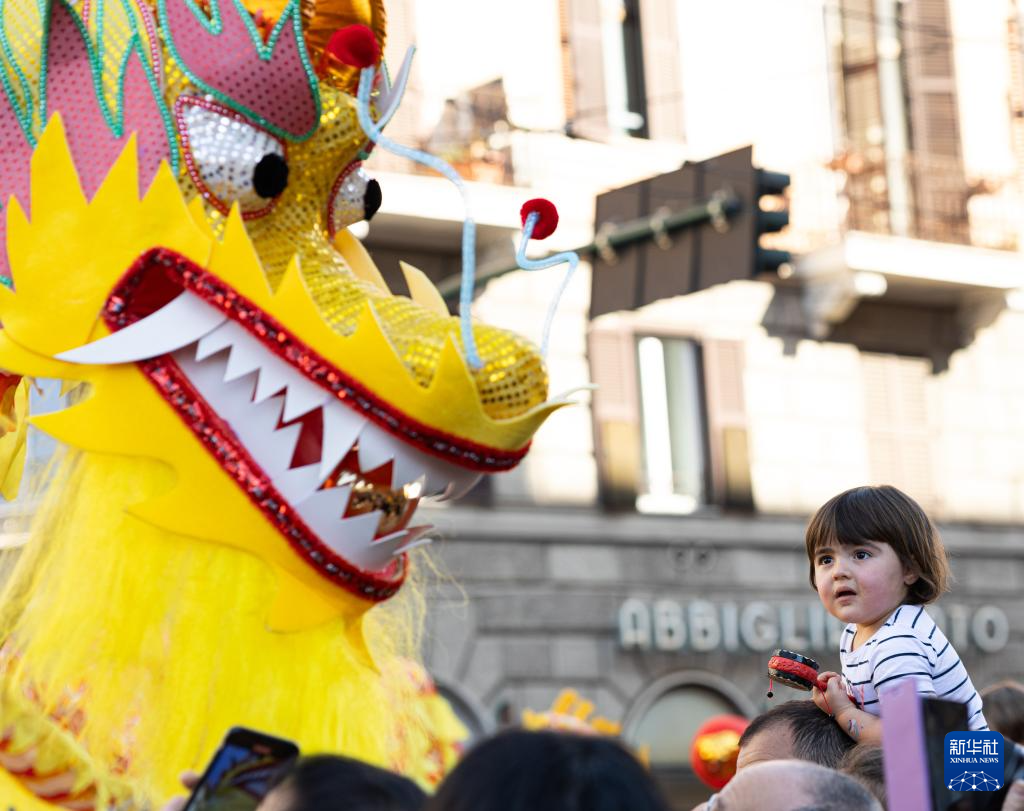 2月18日，在意大利羅馬，一名小朋友在彩妝巡游上觀看舞龍。新華社記者 李京 攝
