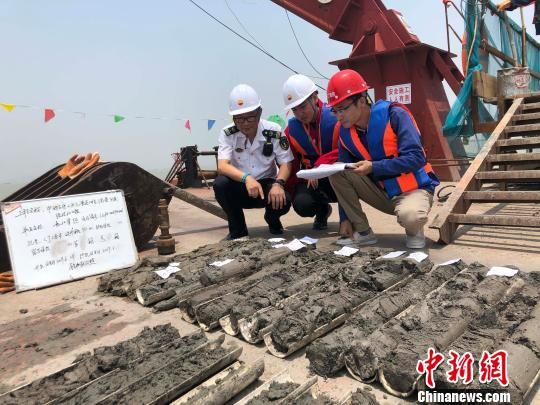 圖為勘察設(shè)計人員與海事局工作人員查看巖芯情況。　魏震 攝