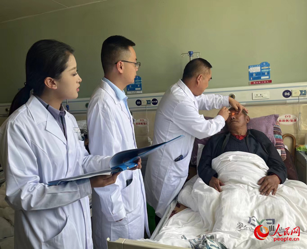 董光明（左三）帶領(lǐng)醫(yī)生對患者進行術(shù)前檢查。人民網(wǎng)記者 杜燕飛攝