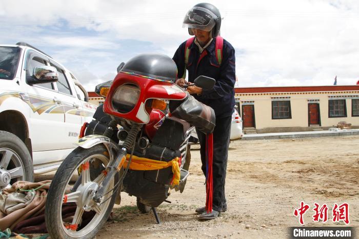 圖為白瑪準(zhǔn)備騎摩托車巡湖。　趙朗 攝