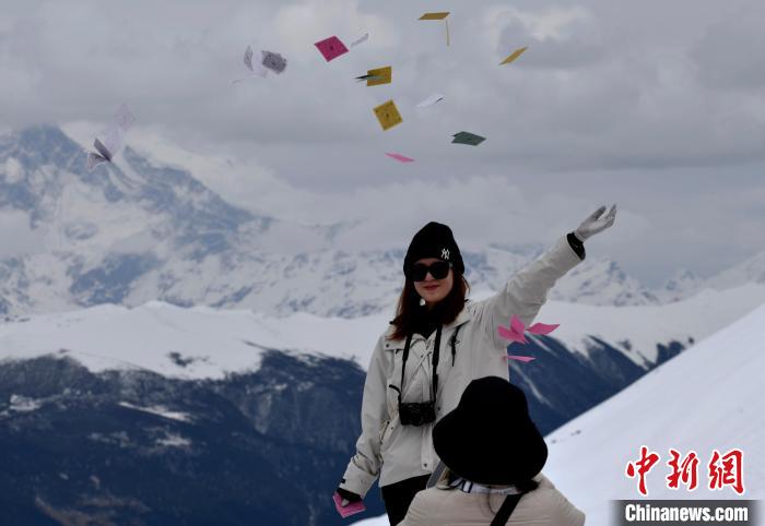 圖為5月14日，游客在西藏林芝色季拉山觀景臺拋灑“隆達”(風(fēng)馬旗，藏族民眾的一種祈福方式)?！±盍?攝