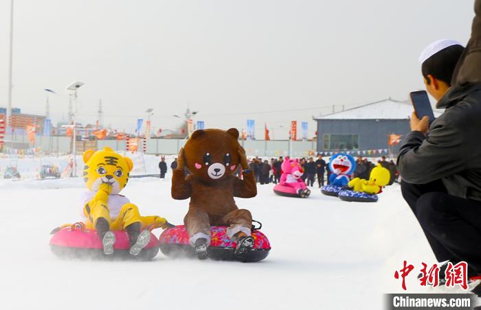 圖為臨夏市南龍鎮(zhèn)馬家莊村舉辦的鄉(xiāng)村文化旅游節(jié)上，游客穿著卡通服裝在體驗(yàn)雪上飛碟項(xiàng)目。近年來(lái)，臨夏州形成了“春賞花、夏避暑、秋摘果、冬玩雪”的全季節(jié)旅游產(chǎn)品體系。(資料圖) 高展 攝