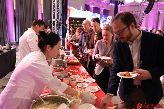 當(dāng)?shù)貢r(shí)間3月7日晚，華盛頓聯(lián)合車站廣場(chǎng)舉行駐美使團(tuán)“使館主廚挑戰(zhàn)賽”。圖為當(dāng)?shù)孛癖娫谥袊?guó)展臺(tái)前體驗(yàn)中國(guó)美食。人民網(wǎng)記者 李志偉攝