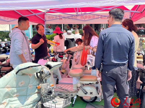 某電動自行車品牌工作人員向消費者介紹以舊換新相關情況。人民網記者 杜燕飛攝