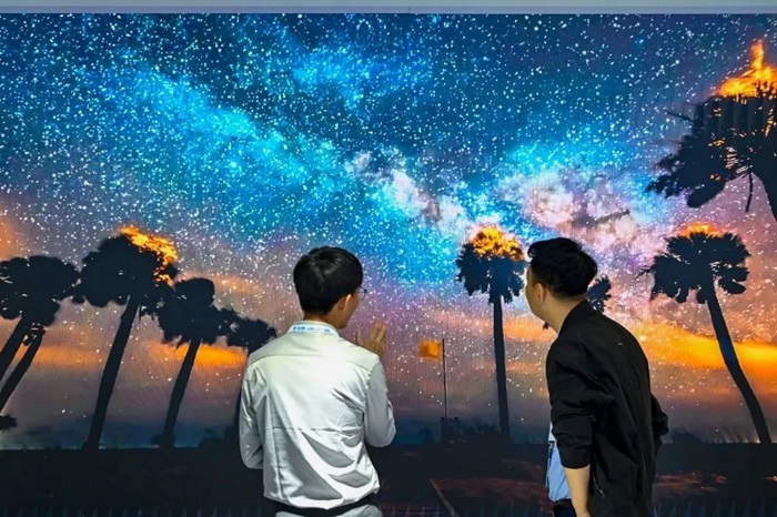 長春光博會希達(dá)電子展區(qū)，一位工作人員正在給一位觀眾講解。（長春新區(qū)供圖）