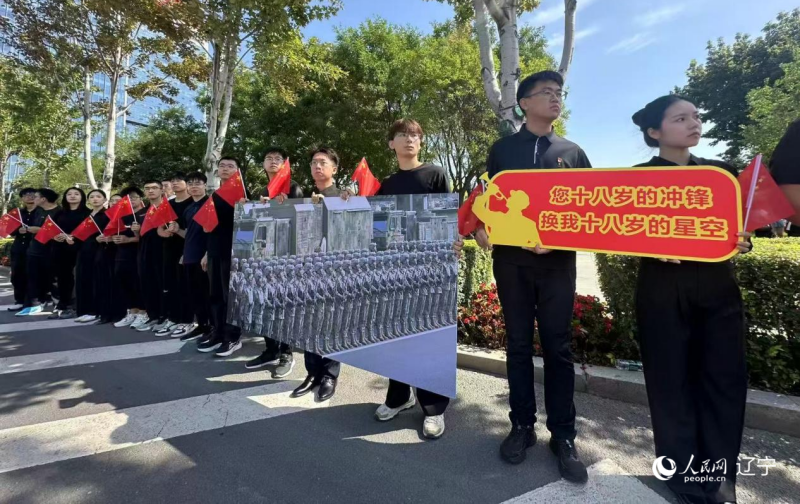 沈陽市人民廣場上，大學生們手持閱兵的圖片，告慰英烈。人民網(wǎng)記者 周頌雪攝