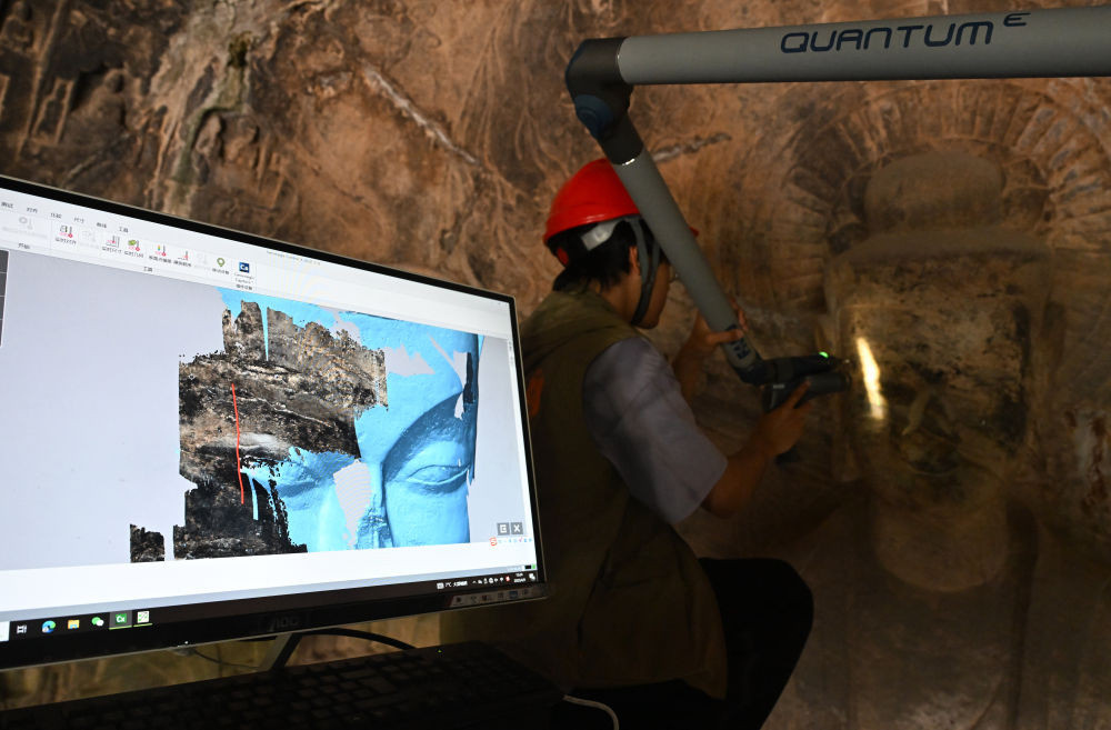 2025年4月9日，武漢大學文化遺產(chǎn)智能計算實驗室團隊成員在魏字洞使用關節(jié)臂掃描儀對佛像進行數(shù)字化掃描。圖片來源新華社