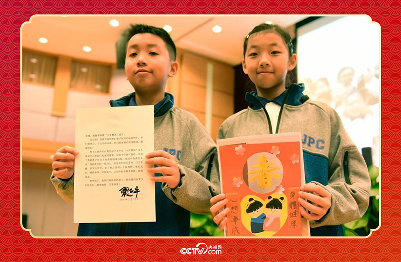 圖為香港“少年警訊”成員郭宏晞（左）展示習主席回信、羅顥凝（右）展示送給習主席的賀卡并合影。