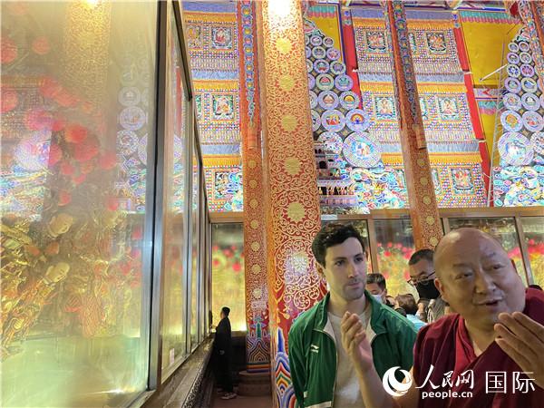 7月25日，省級非物質(zhì)文化遺產(chǎn)項目塔爾寺酥油花的代表性傳承人朋措堅參（右）在塔爾寺酥油花館講解酥油花的制作過程。人民網(wǎng) 謝瑩攝