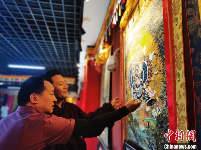 圖為久美尖措展示唐卡作品?！?zhí)砀?攝
