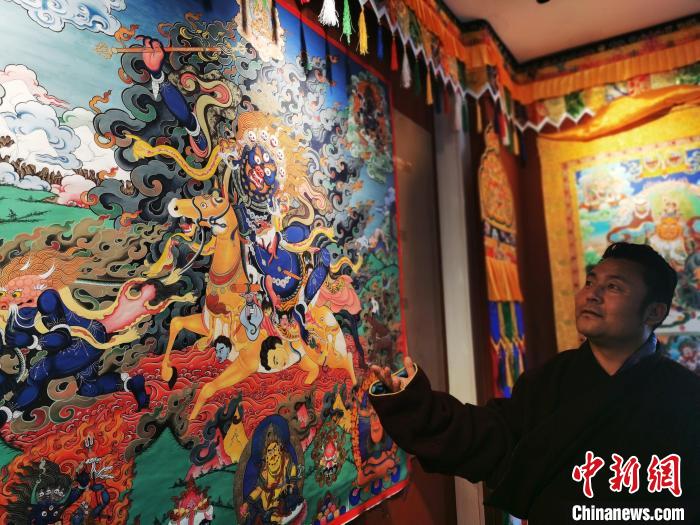 圖為久美尖措展示唐卡作品?！?zhí)砀?攝
