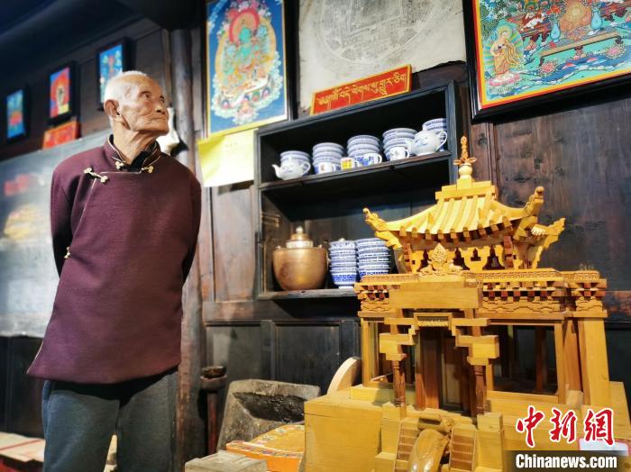 圖為古堡內(nèi)的藝人桑杰展示自己的雕刻作品?！?zhí)砀?攝