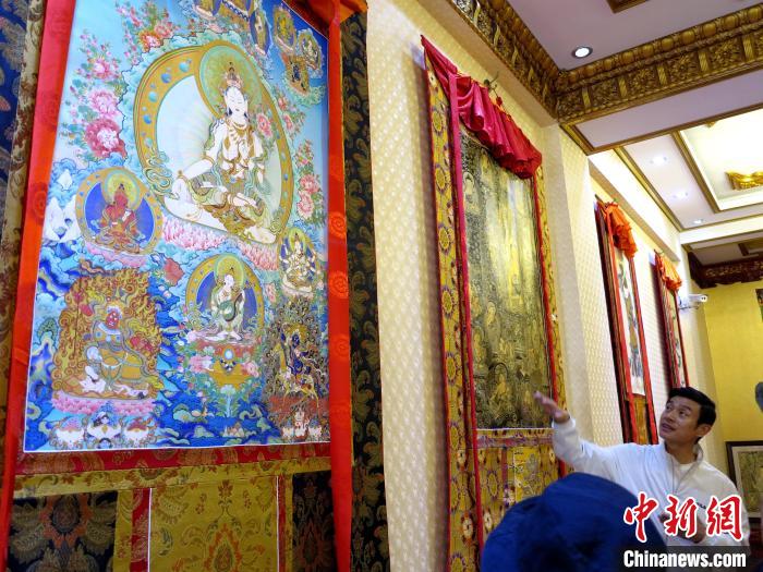 圖為完德尖措展示熱貢龍樹畫苑內(nèi)的唐卡。　張?zhí)砀?攝