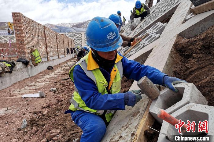 圖為光伏發(fā)電項(xiàng)目施工區(qū)工人在護(hù)坡鋪設(shè)空心磚?！±铍h 攝