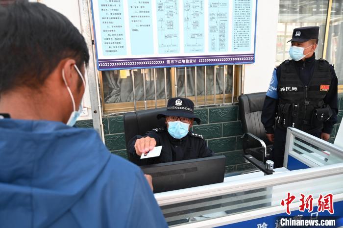 圖為移民管理警察登記完身份信息后將證件歸還給行人?！≮w朗 攝