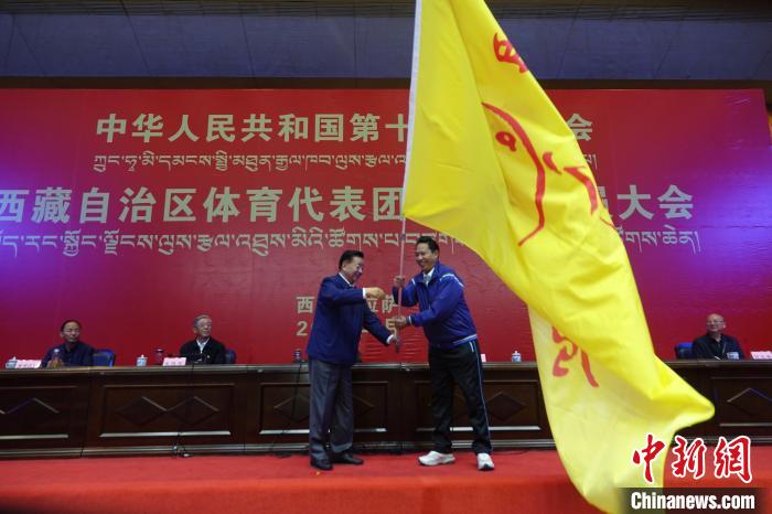 西藏自治區(qū)副主席甲熱·洛桑丹增授代表團(tuán)團(tuán)旗，西藏自治區(qū)體育局局長尼瑪次仁接旗?！∪轿木?攝