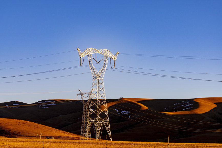 阿里地區(qū)的曠野上，電力鐵塔在夕陽(yáng)下熠熠生輝。