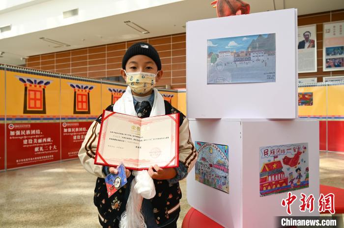 圖為一名獲獎(jiǎng)學(xué)生與自己的繪畫作品合影?！≮w朗 攝