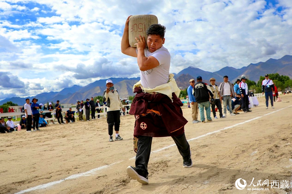來(lái)自拉薩市當(dāng)雄縣的牧民選手將一塊150斤重的石頭扛在肩上飛奔。