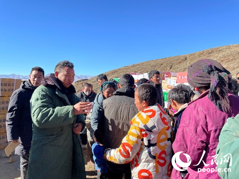 定日縣公安局干警頓珠次仁（左二）正在協(xié)助分發(fā)物資。人民網(wǎng)記者 郝潔攝