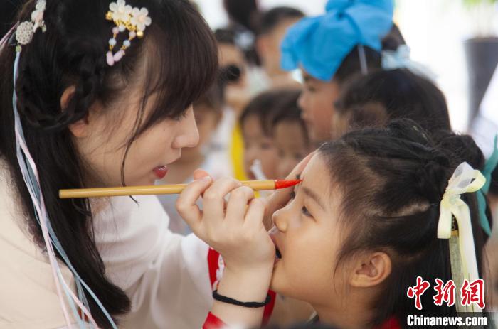 圖為老師在孩子們額頭上點上雄黃，驅(qū)邪辟禍?！《^生 攝