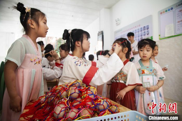 圖為幼兒園的老師們穿上漢服為小朋友們戴上彩蛋，寓意著幸福安康?！《^生 攝